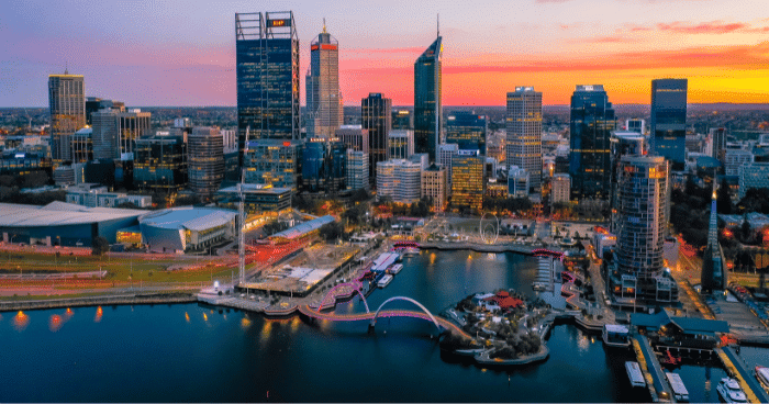 The sun sets over the beautiful Perth city, casting a gradient orange pink sky and over a range of commercial properties and high rises.